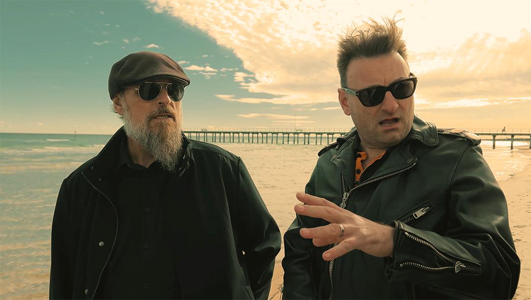 Windswept Clint O'Neil and Rocco Mansbridge walking the beach.